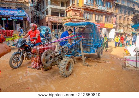 BHAKTAPUR, NEPAL - NOVEMBER 04, 2017: Unidentified people walking close to a small truck at Taumadhi Square in Bhaktapur, Valley, Nepal.
