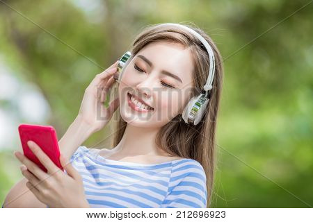 woman smile happily and use phone listen music in the park