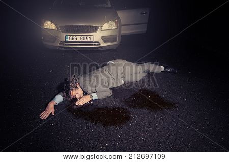 Masked murderer shooting man in suit in front of car on route
