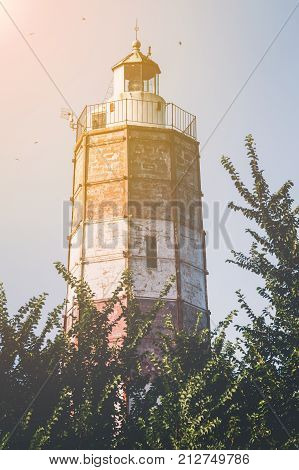 The Cape Shabla lighthouse the oldest on the Bulgarian Black Sea Coast Dobrich Province Bulgaria with its tall hexagonal tower painted red and white for aviation with the sun glow in the corner