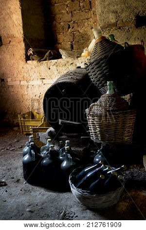 underground wine cellar with mature wine bottles wooden casks and old straw-covered demijohns