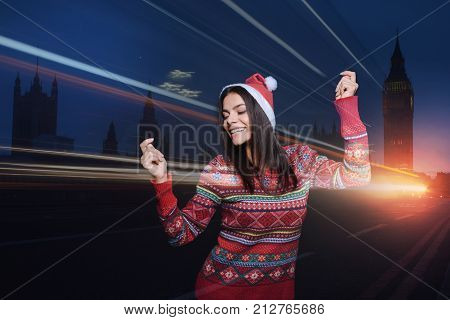 Holiday mood. Cheerful emotional young woman enjoying her holidays while dancing and smiling