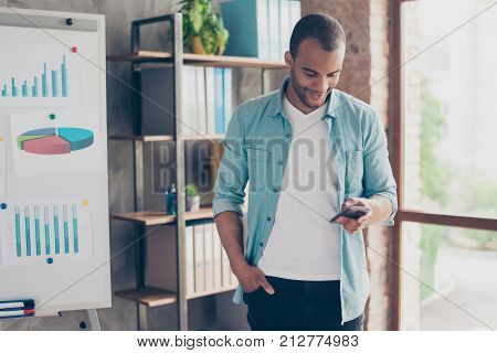 Young Cheerful Afro Freelancer  Is Standing In The Office And Smiling, Reading Good News On Internet