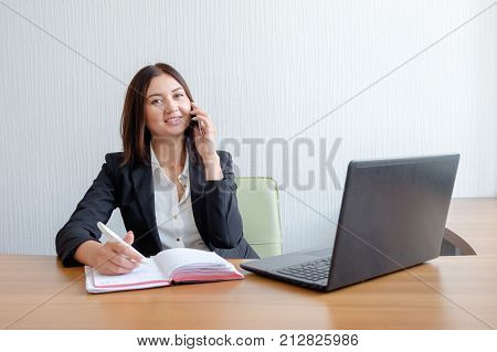 cute young office worker talking on cell phone in office.