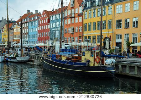 April 20, 2012 Copenhagen, Denmark- Nyhavn waterfront and canal with boats and people walking and eating.