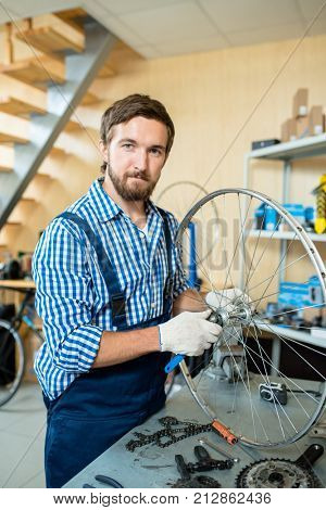 Professional bike repairman fixing wheel center in workshop