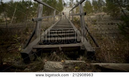 Man man going up stairs. Footage. The old wooden steps on a hill rising on either side grass. Wood stairs up a grass hill HD blur