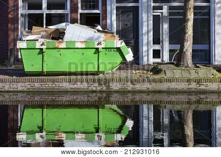 Builders skip and its reflection near a canal in Gouda in the Netherlands