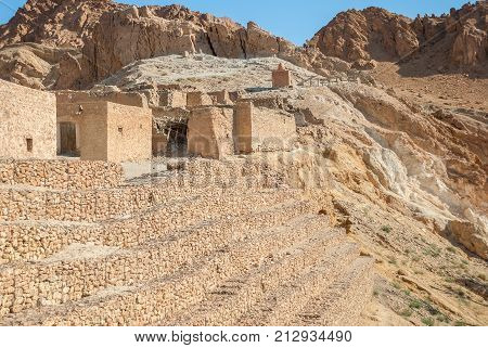 Ruined stone houses of an ancient settlement in the desert against the backdrop of high mountains