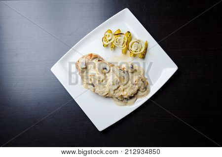 Chicken Breast in Creamy White Wine and Mushroom Sauce on the white plate with potatoes and fried onions
