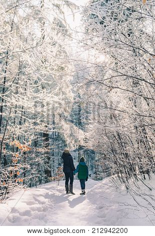 Mother and son walk in snow forest