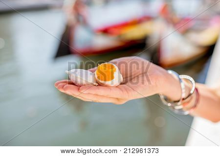 Holding portuguese delicacy called Ovos Moles made of egg yolks and sugar on the water channal background in Aveiro city, Portugal