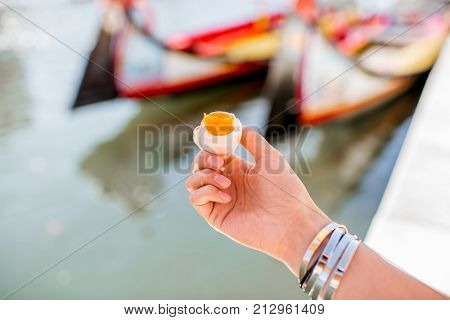 Holding portuguese delicacy called Ovos Moles made of egg yolks and sugar on the water channal background in Aveiro city, Portugal