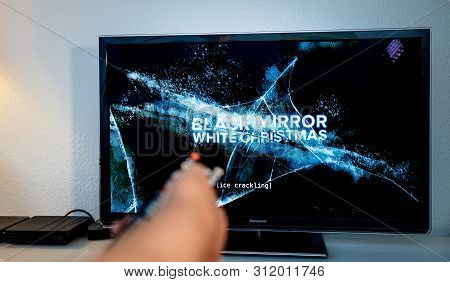 Paris, France - Jul 10, 2019: Senior Man Hand Holding Remote Control Watching The Black Mirror On Ne