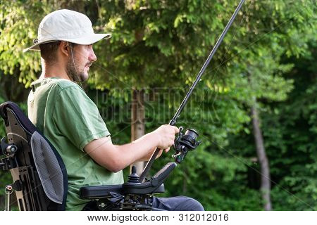 Happy Man In A Electric Wheelchair Fishing At The Beautiful Pond In Natue On A Sunny Day