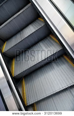 Ribbed Metal-covered Escalator Steps Going Up With Yellow Demarcation  Lines On  Sides