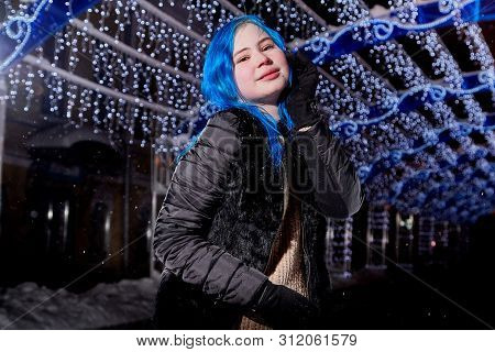 Portrait Of Girl With Blut Hair Skating On The Ice Arena In The Evening City Square In Winter