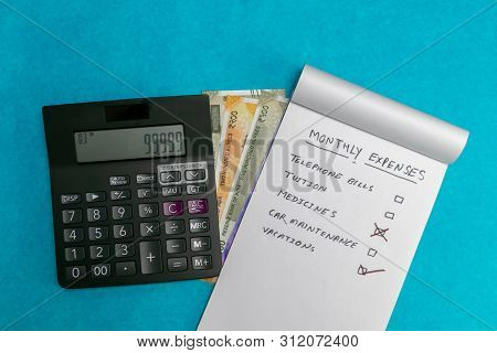 Written Notepad And Calculator On Indian Currency And Blue Background. Medicine  And Expense Concept