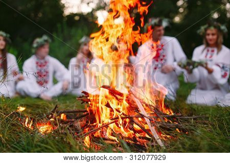 Midsummer. Young People In Slavic Clothes Sitting In The Woods Near The Fire.