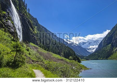 Alps Mountains With Blue Lake And Waterfall. Photo Taked At Stillup Lake, Austria, Tyrol Region