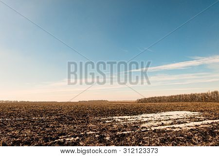 Early Spring Scene. Field With Snowy Thawed Patches Under A Sunny Blue Sky.