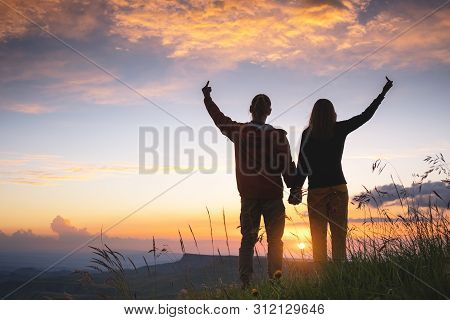 Silhouettes Of A Young Millennial Couple With Raised Hands And A Gesture Middle Finger In Love With 