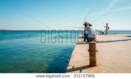 Didim, Turkey - October 03, 2017: Group Of People Fishing Under The Sun In Didim, Turkey. Leisure Co
