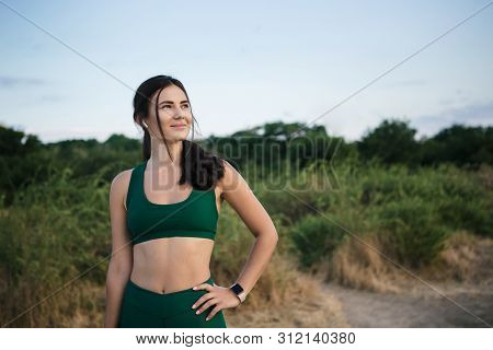 Pretty Brunette Woman Resting After Mornong Jogging At The Sea Shore At Sunrise Listening To The Mus