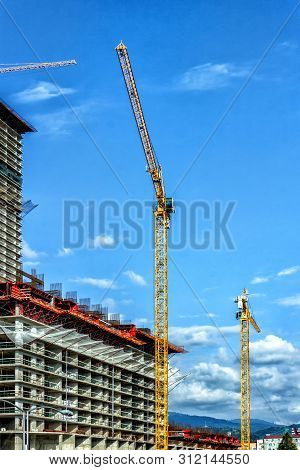 Towers Of The Cranes. Construction Site With Cranes Against The Blue Sky.