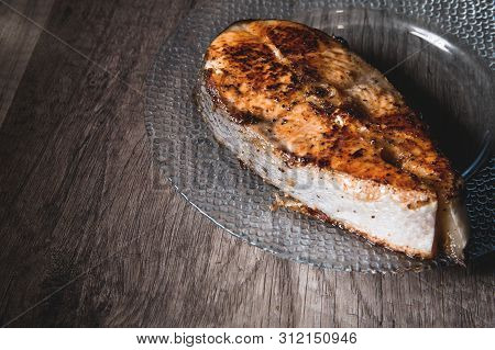 Close-up One Grilled Cum Salmon Keta Fish Steak On A Glass Transparent Plate On A Dark Wood Table Ba