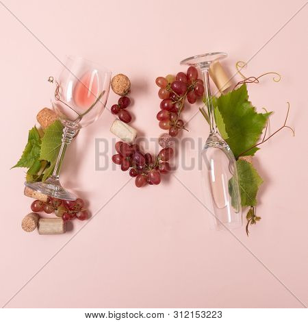 Alphabet. Letter M Made Of Wineglasses With Rose And White Wine, Grapes, Leaves And Corks Lying On P