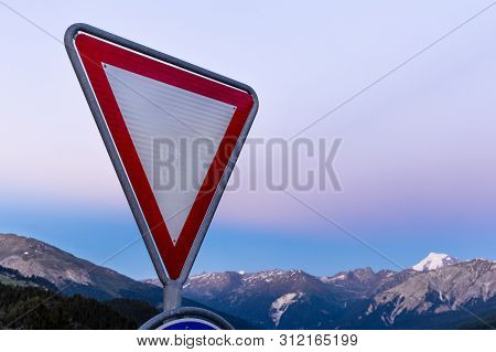 Road Sign Give Way To Alpine Mountains Background.