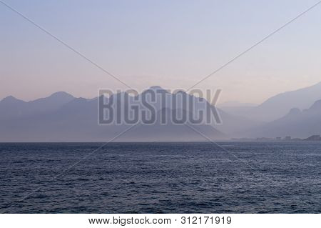 Mountains In A Blue Haze And Sunset Over The Sea