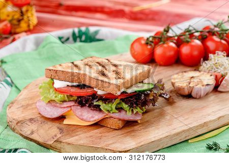 New Years Sandwich With Sausage, Tomatoes, Cheese, Sauce And Lettuce On A Wooden Board. Against The 