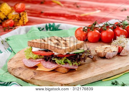 New Years Sandwich With Sausage, Tomatoes, Cheese, Sauce And Lettuce On A Wooden Board. Against The 