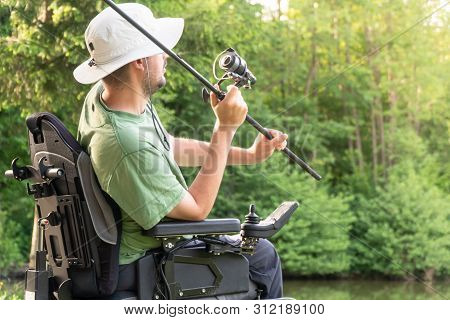 Happy Man In A Electric Wheelchair Throwing Fishing Pole At The Beautiful Pond In Natue On A Sunny D