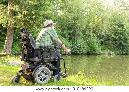 Happy Man In A Electric Wheelchair Throwing Fishing Pole At The Beautiful Pond In Natue On A Sunny D