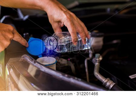 Mechanic Fill Fresh Water Into Windscreen Or In Water Tank Wiper On Car Engine Room. Service And Mai