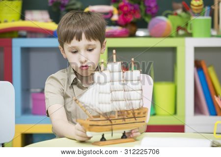 Boy Playing With Ship.child With A Toy Sailboat
