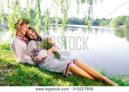 Midsummer. Young Loving Couple In Slavic Costumes On The Shore Of The Lake. Slavonic Holiday Of Ivan
