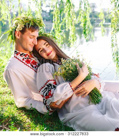 Midsummer. Young Loving Couple In Slavic Costumes On The Shore Of The Lake. Slavonic Holiday Of Ivan