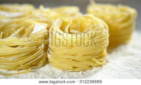 Fettuccine, Raw Pasta, Closeup Lie In White Flour On A Wooden Table