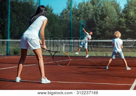 Dark-haired Wife Playing Tennis With Husband And Son