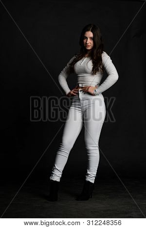 Young Lady With Hair In Topknot Standing With Arms Folded Looking Up. Capricious Female Model In Gre