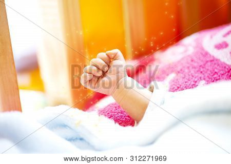 Hand Of An Energetic Newborn Baby With Light Blue And Pink Blanket And Baby Bed. Close Up.