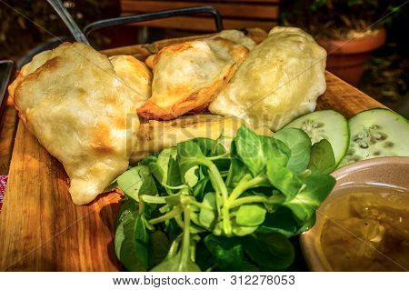 Roasted Polish Pierogi, Pyrohy Or Dumplings, Varenyky, Vareniki, On The Wooden Board With Green Sala