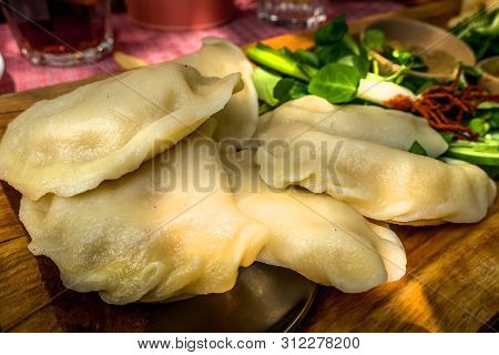 Varenyky, Vareniki, Polish Pierogi, Pyrohy Or Dumplings On The Wooden Board With Green Salad, Tradit