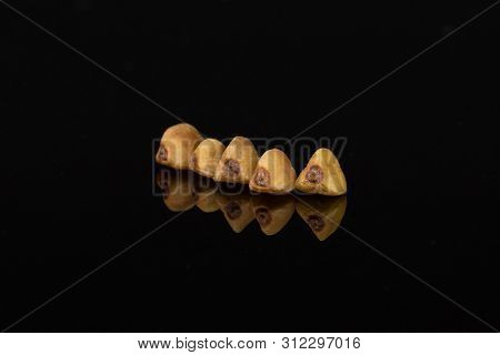 Group Of Five Whole Raw Brown Buckwheat Grain Isolated On Black Glass