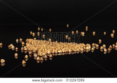 Lot Of Whole Common Raw Brown Buckwheat Grain Isolated On Black Glass