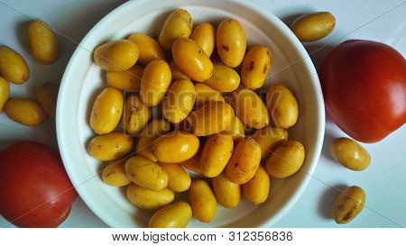 Fresh Barhi Dates In Plate With Two Red Tomatoes